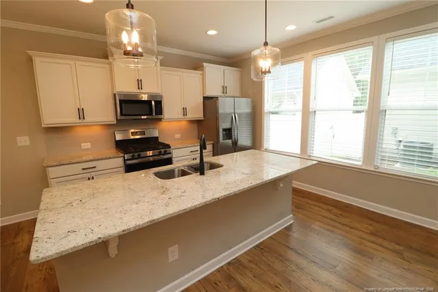 a kitchen with stainless steel appliances granite countertop a sink a stove and a wooden floors