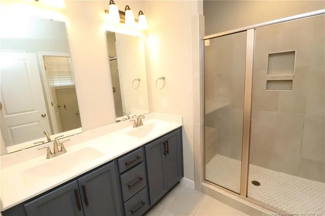 a bathroom with a double vanity sink mirror and shower