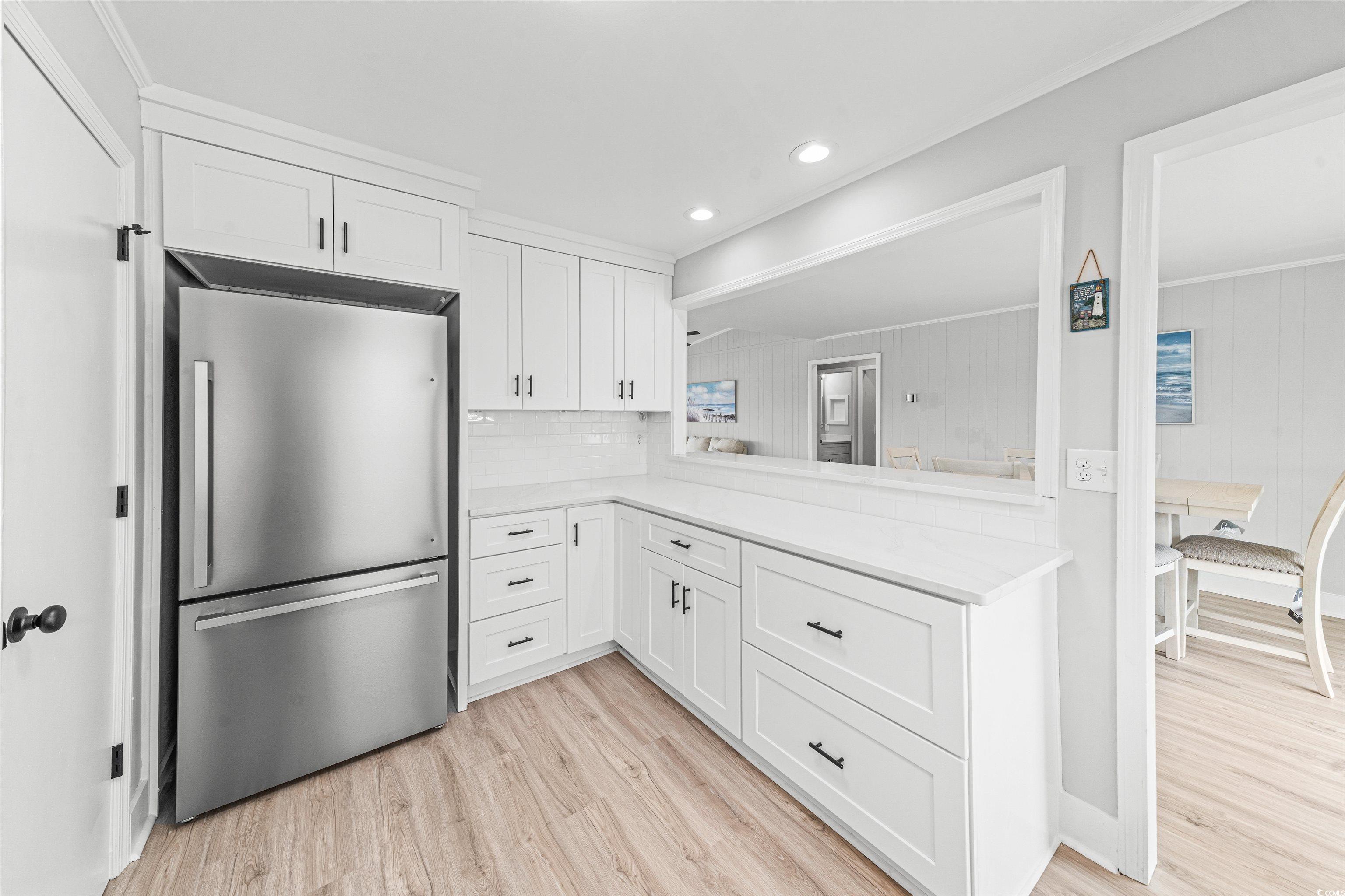338 State Rd S-26-530 Murrells Inlet, SC 29576 - Photo 15 of 39 Kitchen with light countertops, freestanding refrigerator, light wood-style flooring, white cabinets, and decorative backsplash