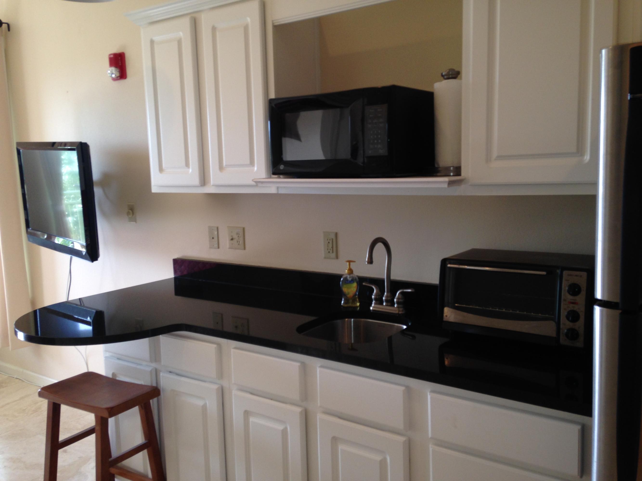 9955 Co Road, Unit 200 Seacrest, FL 32461 - Photo 14 of 17 a kitchen with granite countertop white cabinets and black appliances