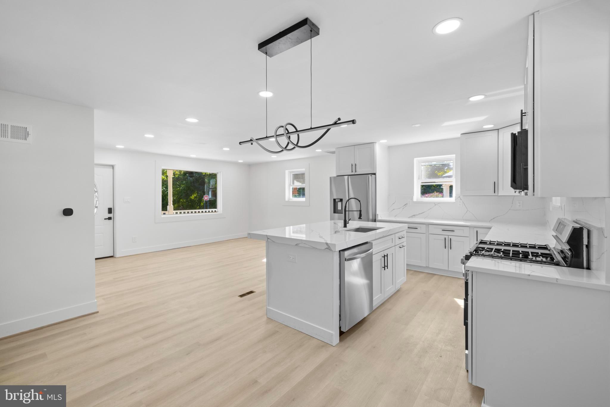 4821 Topping Road Rockville, MD 20852 - Photo 11 of 45 a kitchen with a stove a sink a refrigerator and white cabinets with wooden floor
