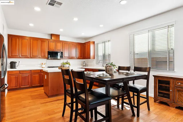 a kitchen with stainless steel appliances granite countertop wooden floor a dining table and chairs