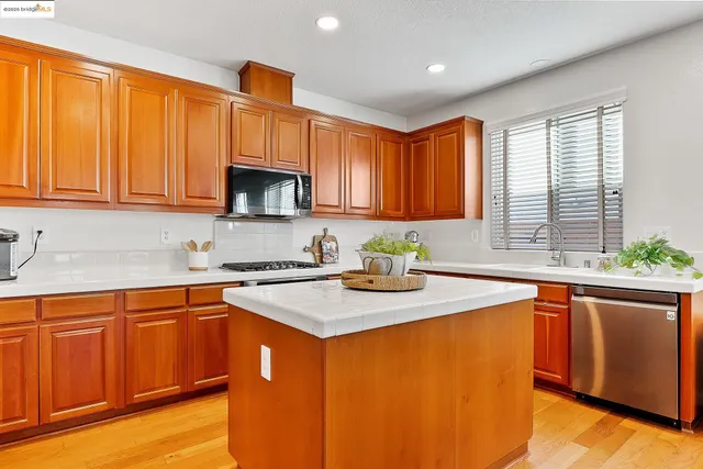 a kitchen with stainless steel appliances granite countertop wooden cabinets a sink and a window