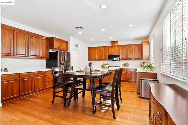 a kitchen with stainless steel appliances granite countertop wooden floor a dining table and chairs