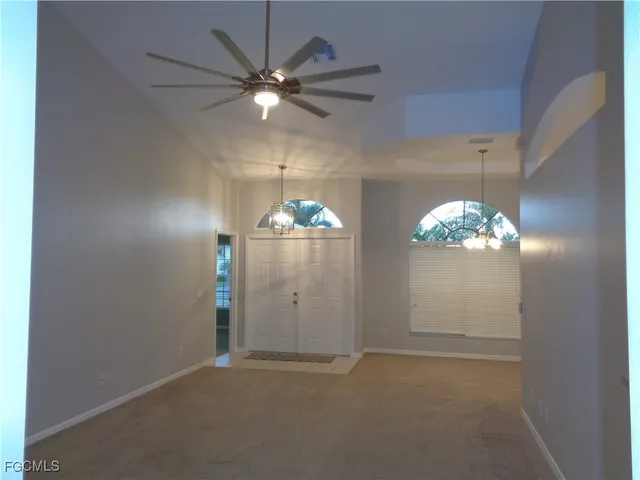 en empty room with window chandelier fan and refrigerator