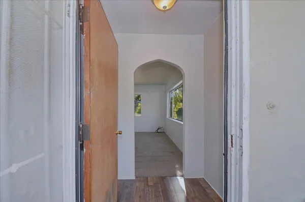 a view of an empty room with wooden floor and a window
