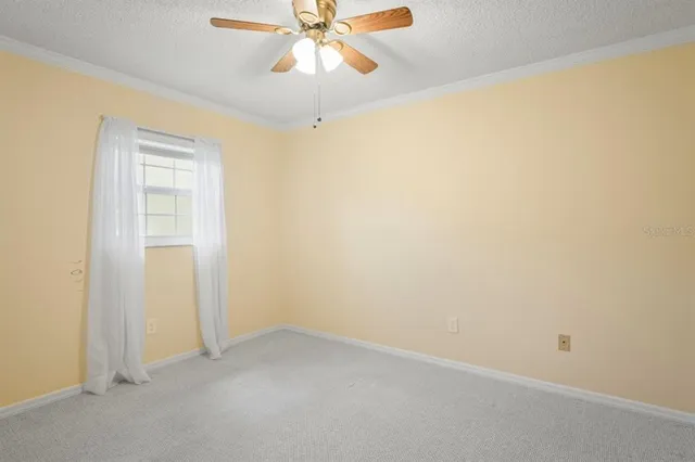 an empty room with a window and a chandelier fan