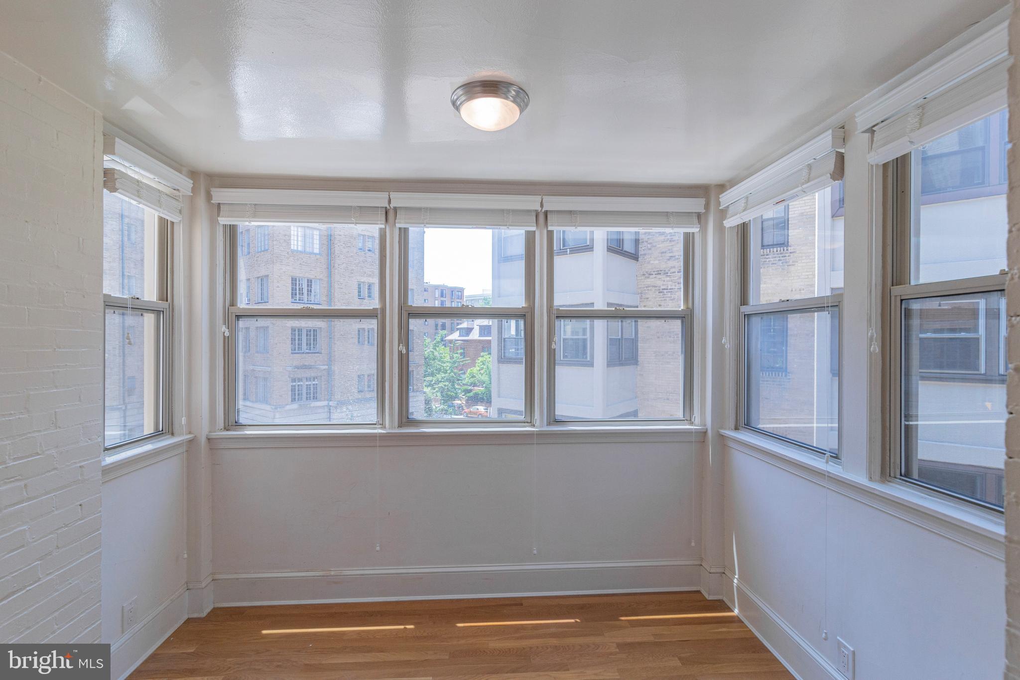 1910 Kalorama Road Northwest, Unit 307 Washington, DC 20009 - Photo 14 of 19 a view of an empty room with wooden floor and a window