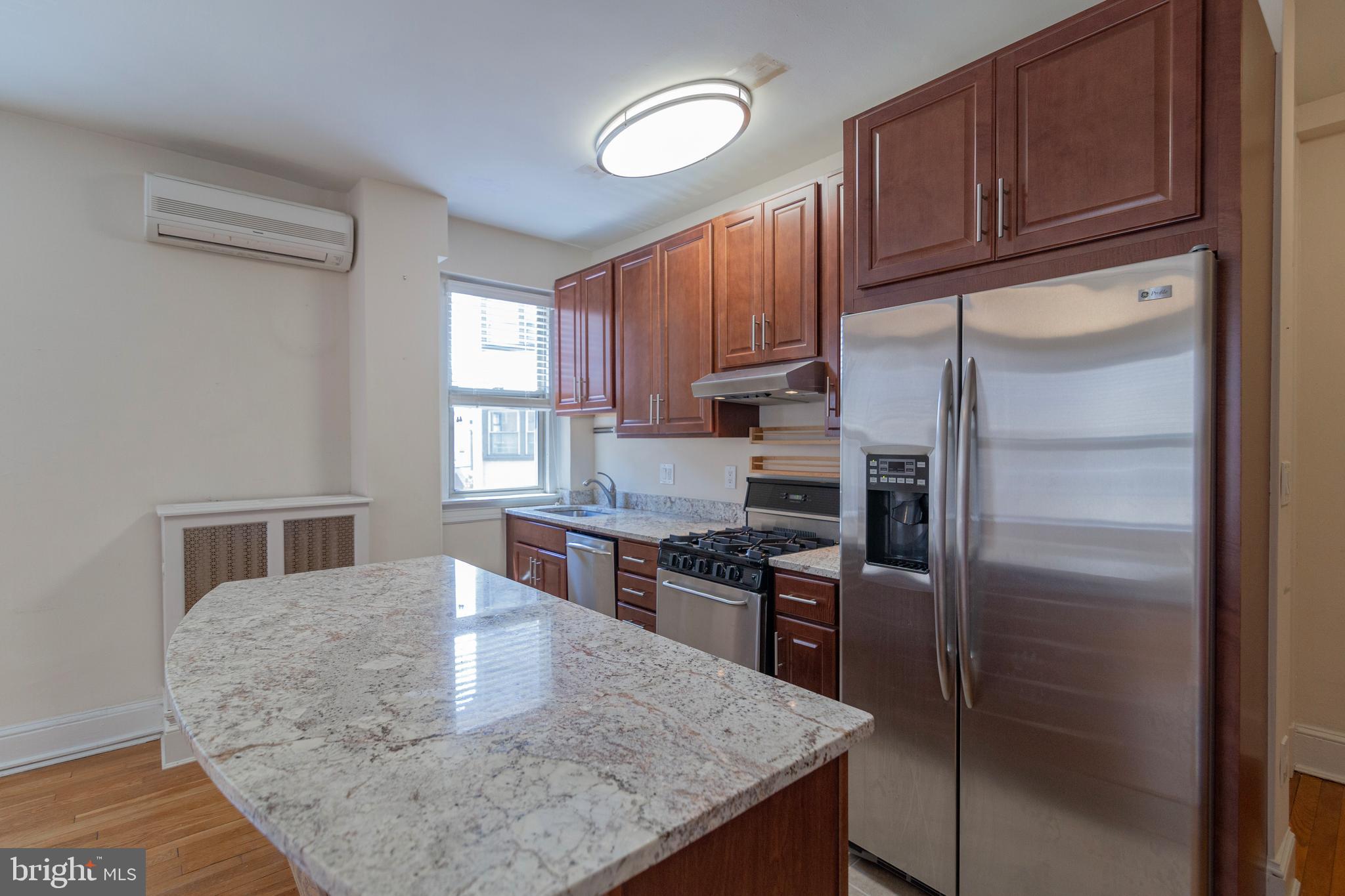 1910 Kalorama Road Northwest, Unit 307 Washington, DC 20009 - Photo 7 of 19 a kitchen with stainless steel appliances granite countertop a refrigerator a stove and a sink with wooden cabinets