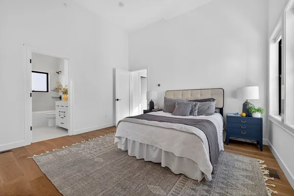 a spacious bedroom with a bed and wooden floor