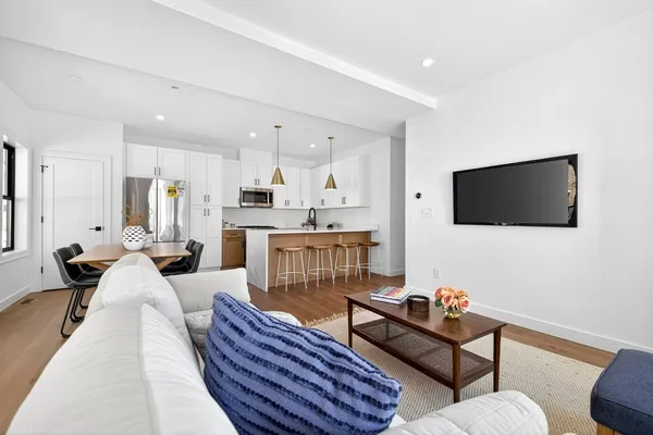 a living room with furniture a flat screen tv and kitchen view