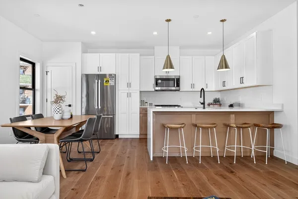 a kitchen with stainless steel appliances granite countertop a stove a sink a dining table and chairs with wooden floor