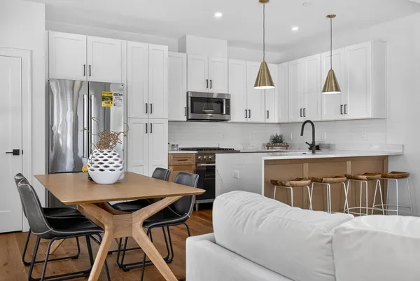 a kitchen with stainless steel appliances granite countertop a kitchen island a table and chairs