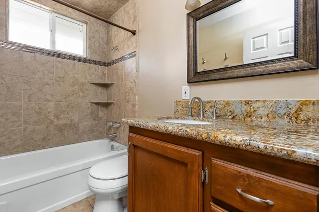 a bathroom with a granite countertop sink a toilet and bathtub