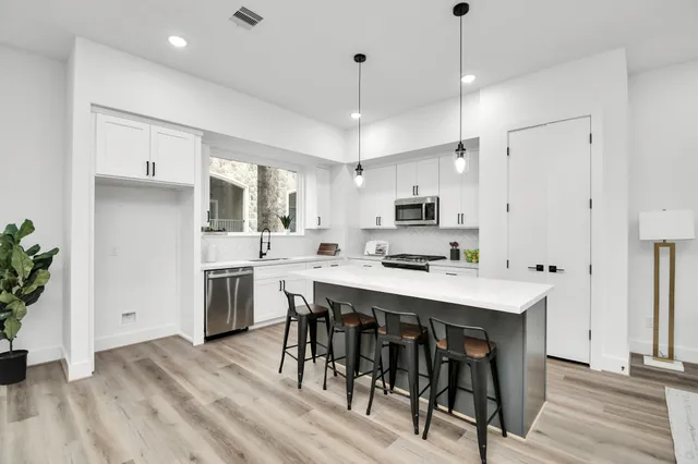 a kitchen with stainless steel appliances kitchen island a table chairs refrigerator and microwave