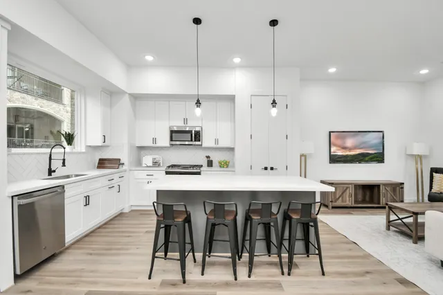 a large kitchen with stainless steel appliances kitchen island granite countertop a stove a sink a dining table and chairs with wooden floor