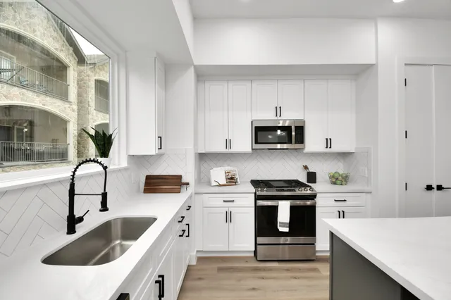 a kitchen with granite countertop white cabinets and black stainless steel appliances