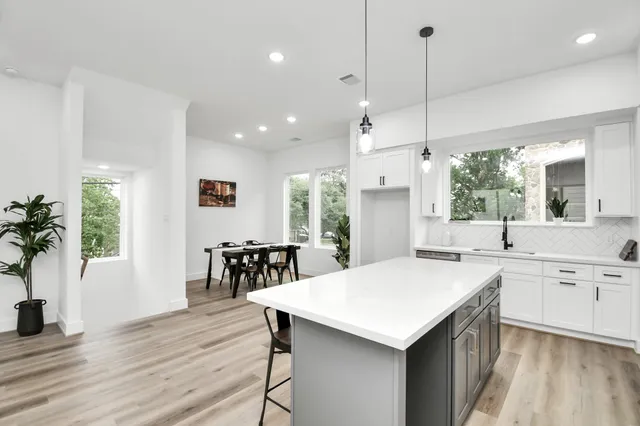 a kitchen with a kitchen island hardwood floor sink stove dining table and chairs