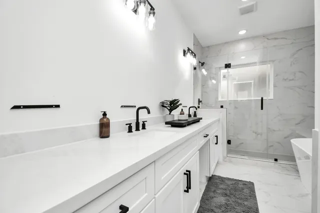 a bathroom with a double vanity sink a toilet and shower