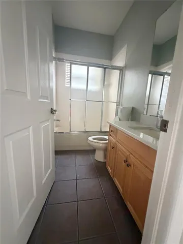 a bathroom with a granite countertop sink a toilet a mirror and a tub
