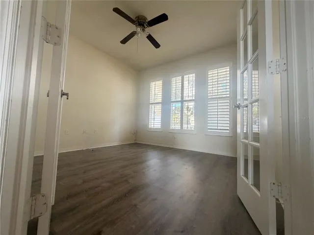a view of empty room with wooden floor and fan