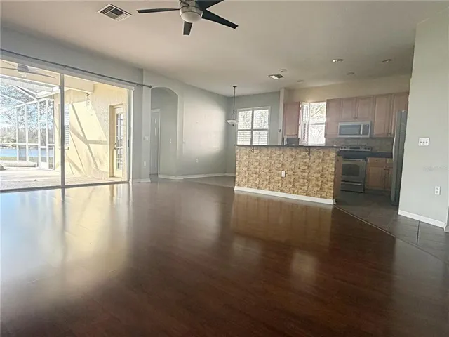a view of an empty room with a window and wooden floor