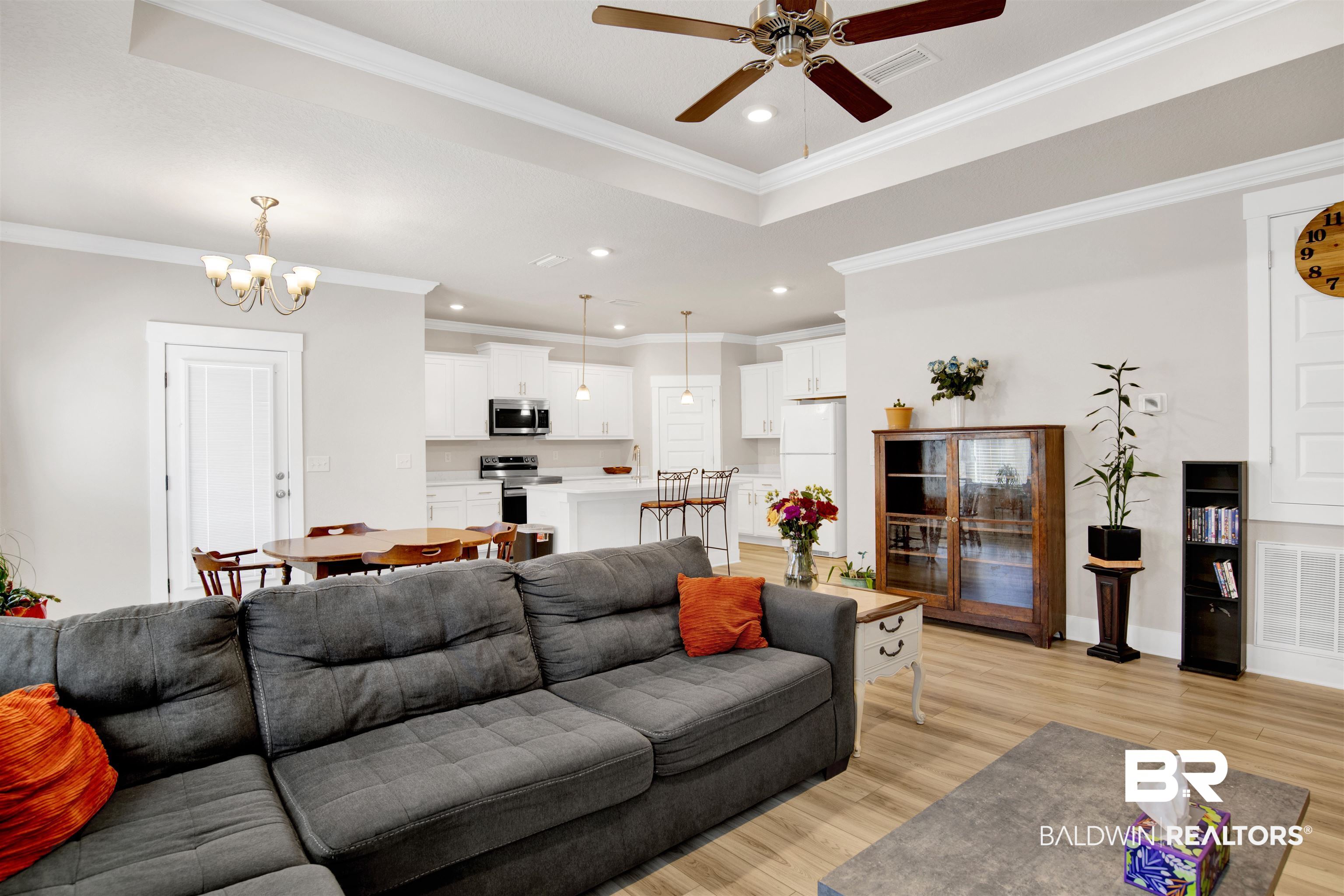 1174 Pheasant Circle Foley, AL 36535 - Photo 7 of 29 Living area with light wood-type flooring, a ceiling fan, a chandelier, crown molding, and a tray ceiling