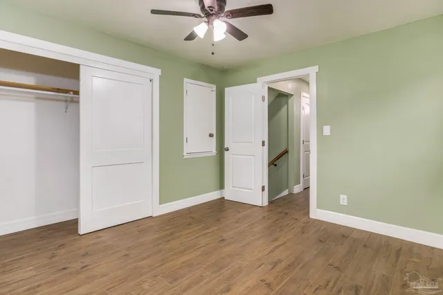 an empty room with wooden floor and a ceiling fan
