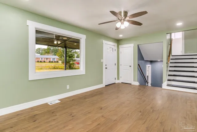 a view of an empty room with a window and wooden floor