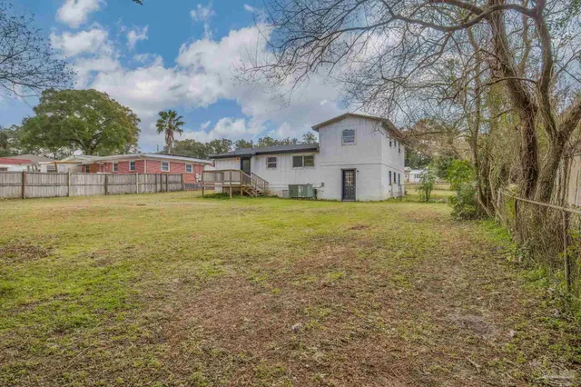 a view of a house with a yard and a large tree