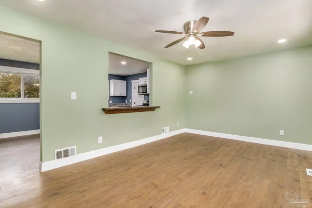 a view of a room with wooden floor and a ceiling fan