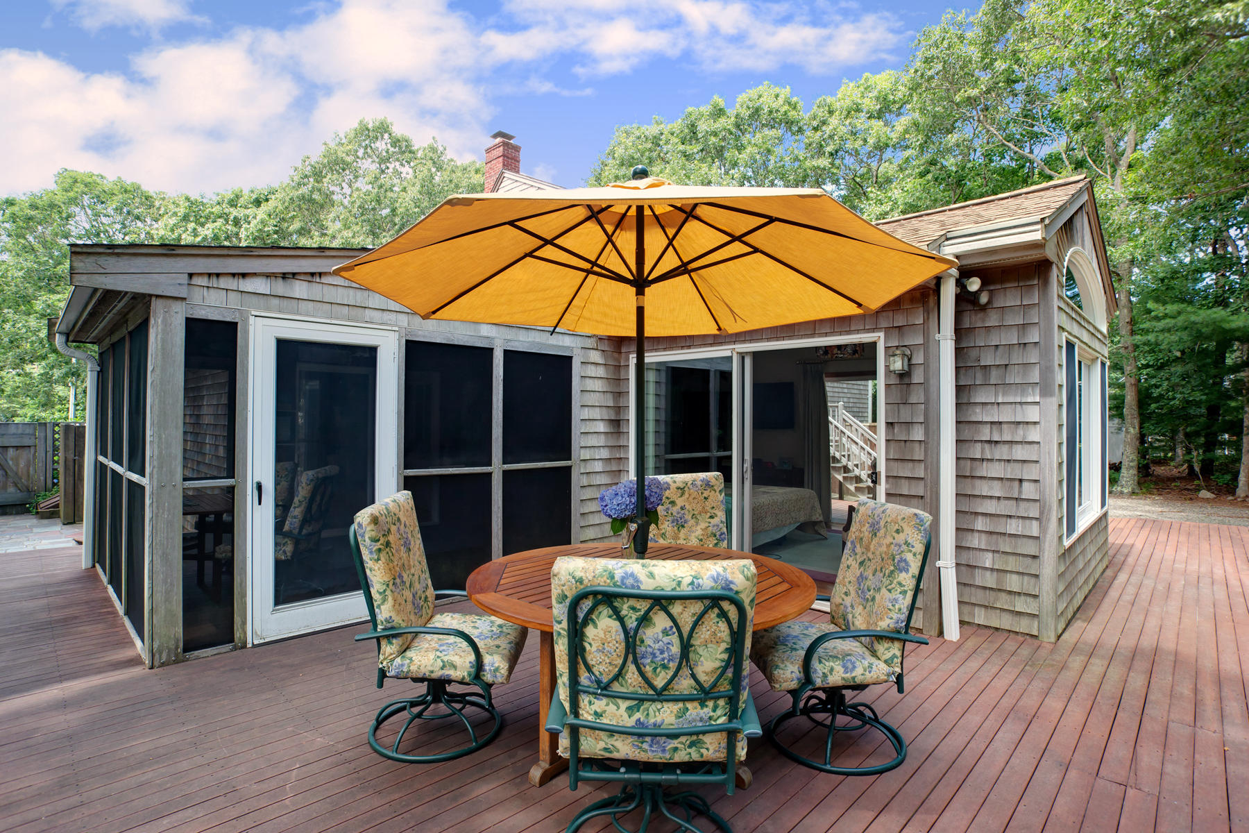 18 Frederick Road Falmouth, MA 02540 - Photo 32 of 62 a patio table and chairs under an umbrella with wooden floor and fence