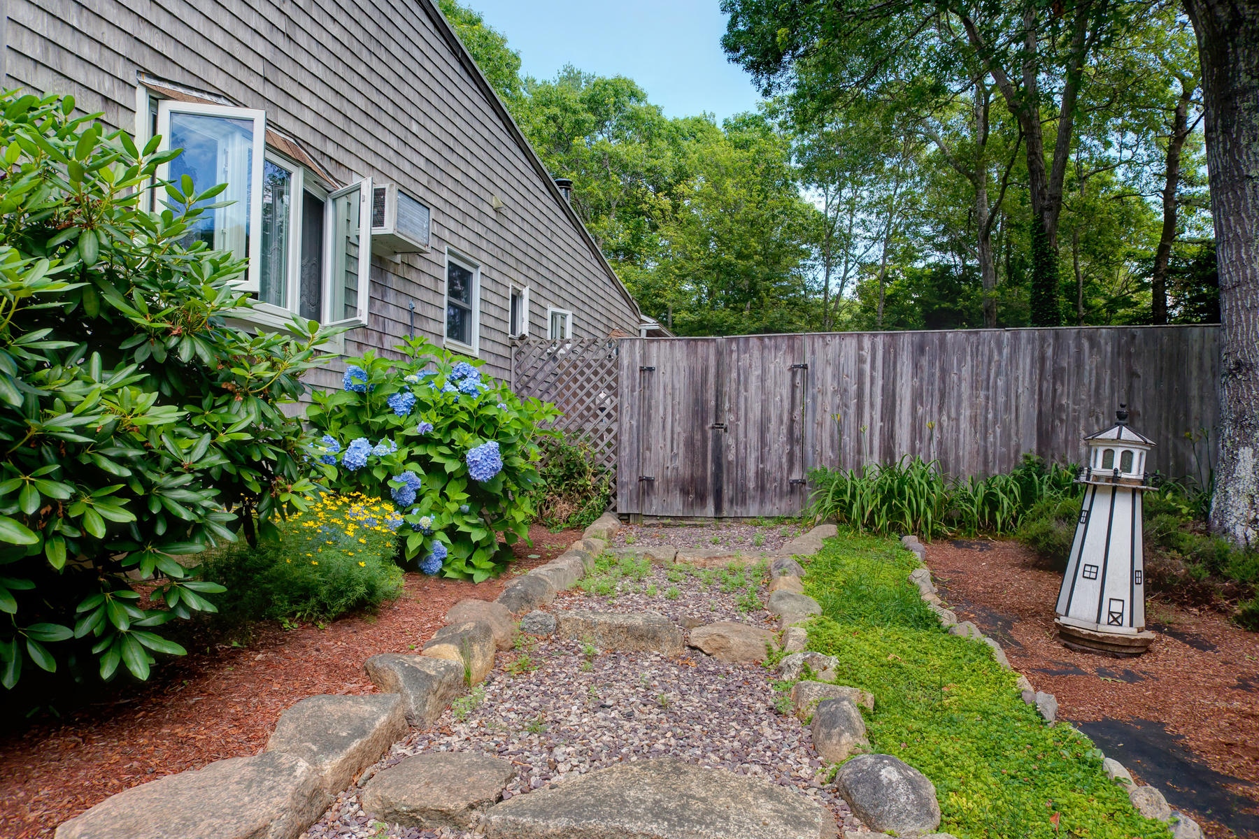 18 Frederick Road Falmouth, MA 02540 - Photo 36 of 62 a view of a backyard with plants and large trees with wooden fence