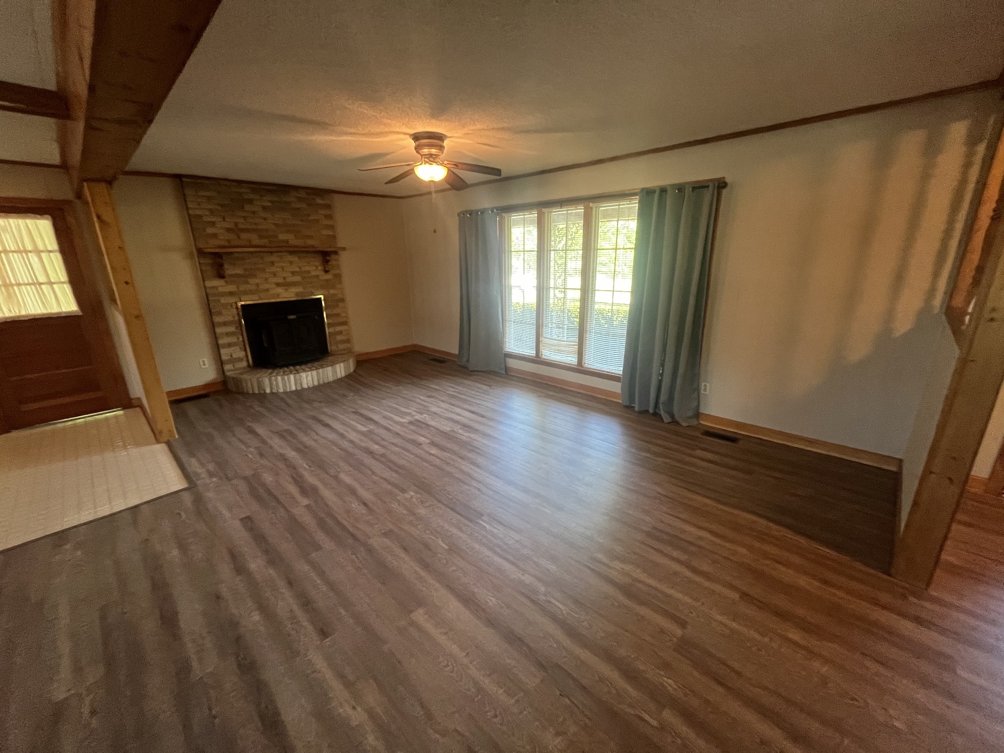 1619 Railroad Bed Road Collinwood, TN 38450 - Photo 10 of 54 an empty room with wooden floor fireplace and windows