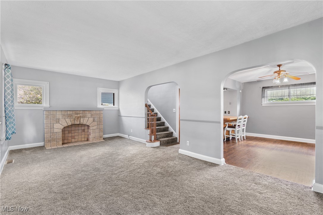 302 Poplar Avenue Northwest Canton, OH 44708 - Photo 7 of 34 Unfurnished living room featuring carpet flooring, arched walkways, plenty of natural light, and stairs