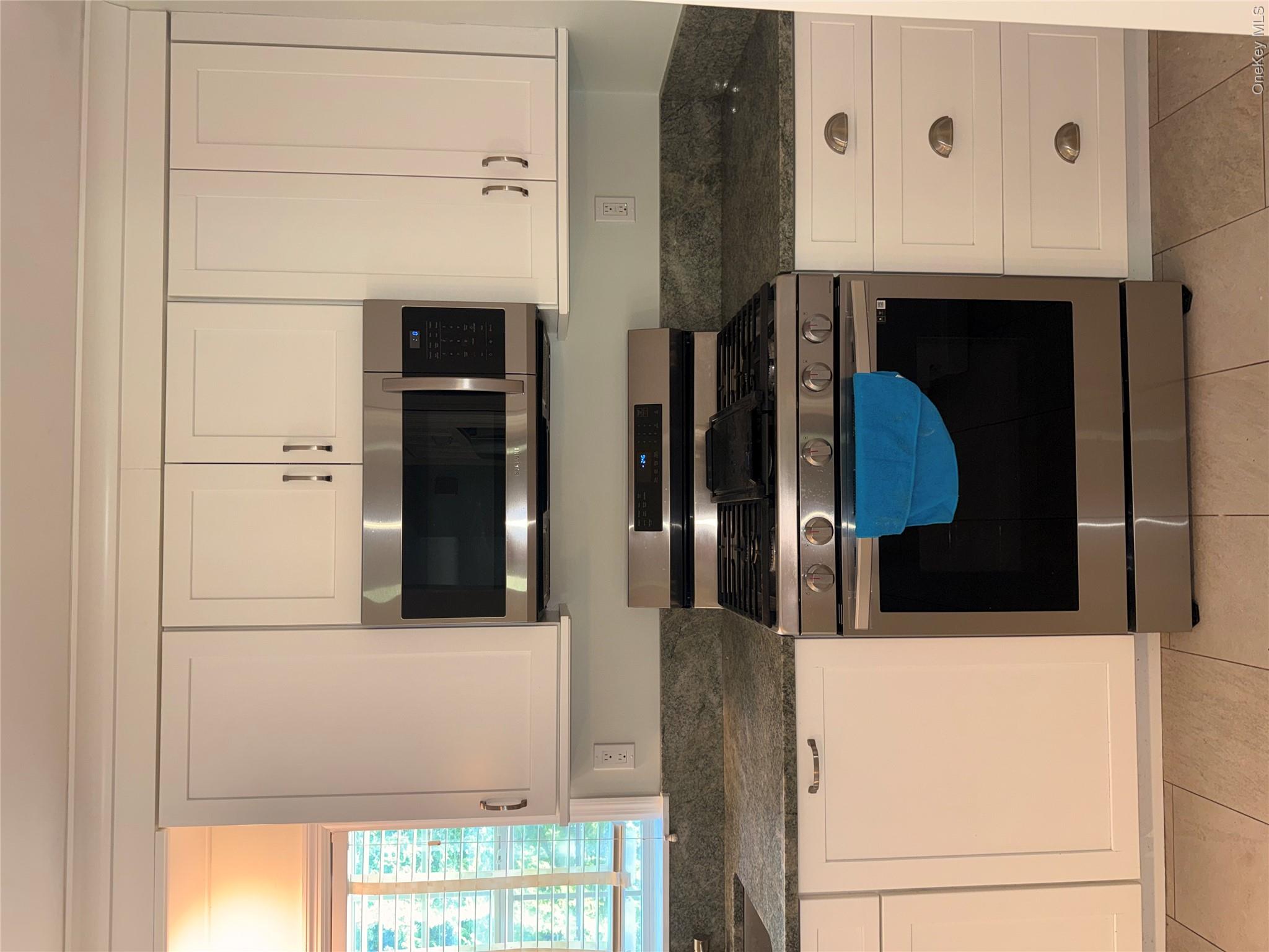 1661 Old Country Road, Unit 516 Riverhead, NY 11901 - Photo 17 of 50 a kitchen with granite countertop a stove a microwave and white cabinets