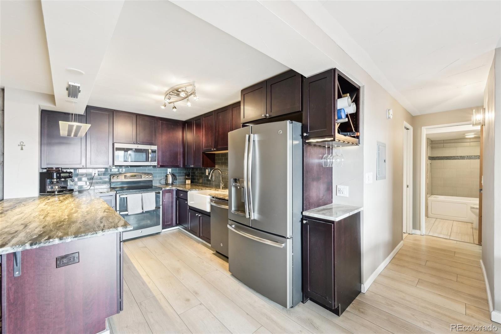 2 Adams Street, Unit 705 Denver, CO 80206 - Photo 13 of 50 a kitchen with stainless steel appliances granite countertop a refrigerator a stove and a sink with wooden floor