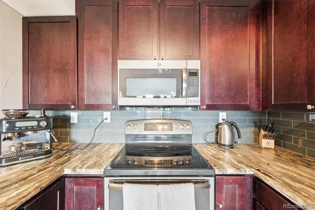 a kitchen with granite countertop a stove a sink and a microwave