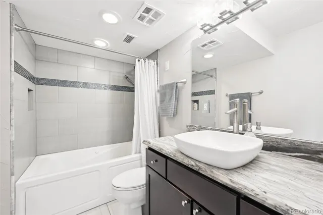 a bathroom with a granite countertop sink a toilet a mirror and shower