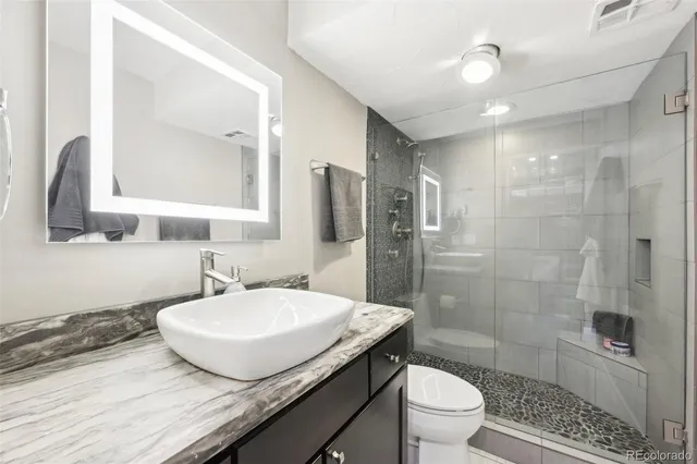 a bathroom with a granite countertop sink toilet a mirror and shower