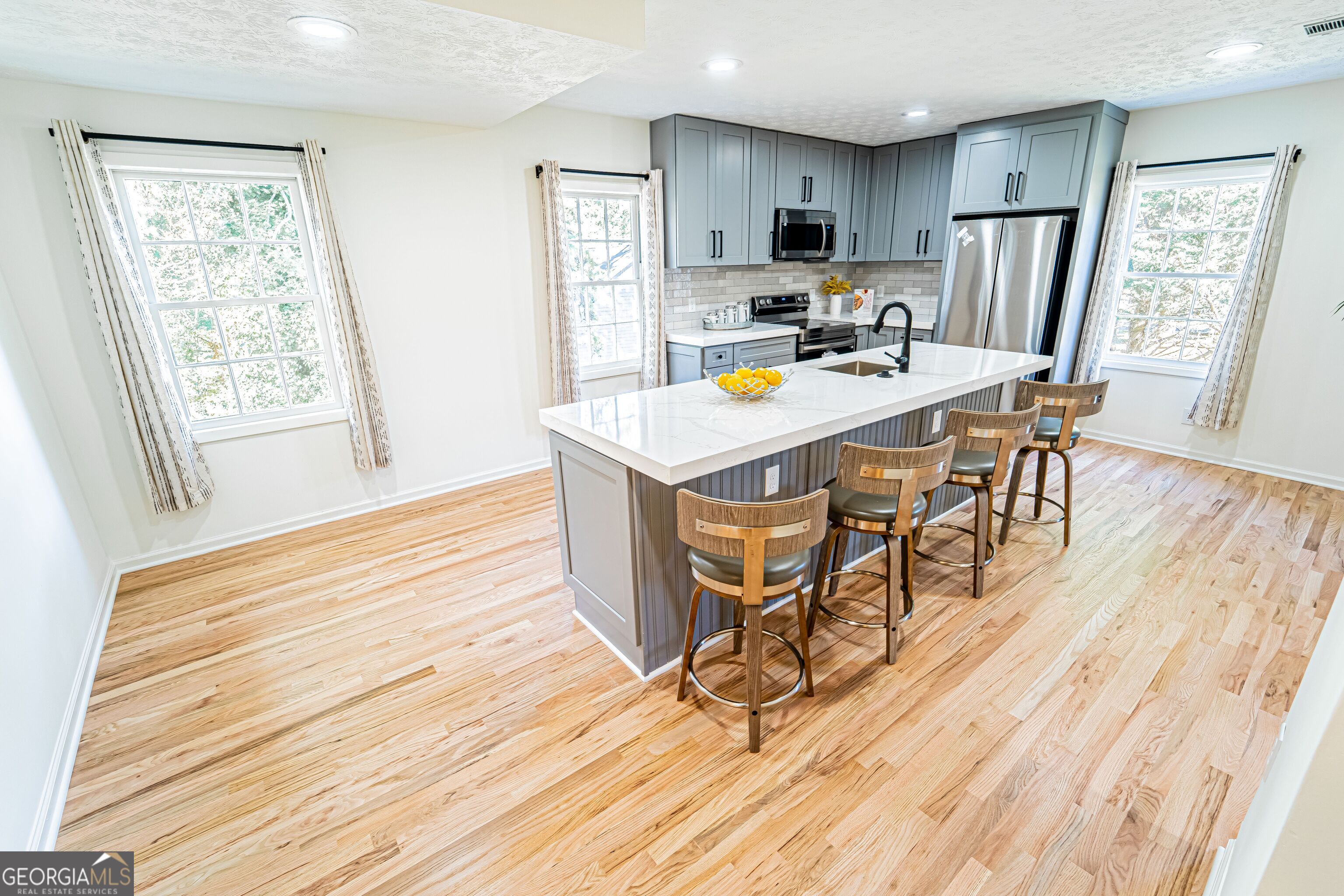 5205 Corinth Circle, Unit 3 Stone Mountain, GA 30087 - Photo 20 of 22 a kitchen with stainless steel appliances a stove a refrigerator a microwave oven with a dining table and chairs with wooden floor