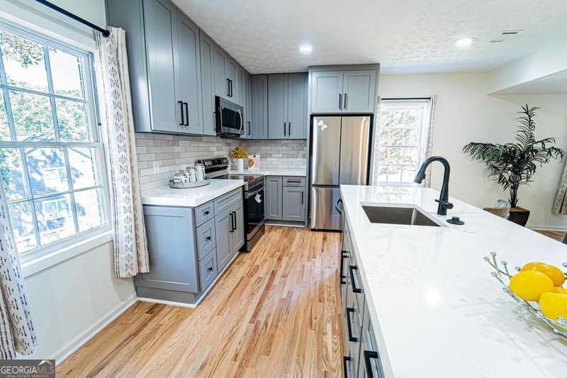 5205 Corinth Circle, Unit 3 Stone Mountain, GA 30087 - Photo 5 of 22 a kitchen with sink a refrigerator and wooden cabinets