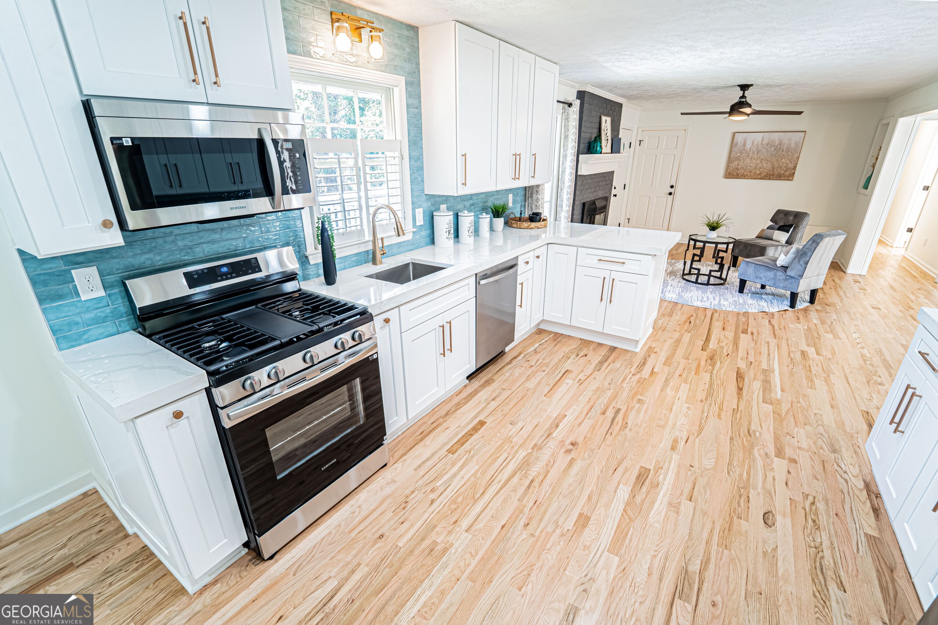 5205 Corinth Circle, Unit 3 Stone Mountain, GA 30087 - Photo 6 of 22 a kitchen with stainless steel appliances a stove a sink a microwave and wooden floors