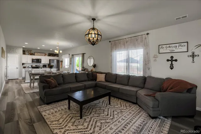 a living room with furniture kitchen view and a chandelier