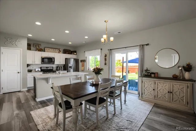 a kitchen with stainless steel appliances granite countertop a stove a sink dishwasher a dining table and chairs with wooden floor