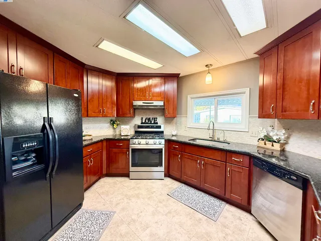 a kitchen with granite countertop wood cabinets stainless steel appliances and a sink