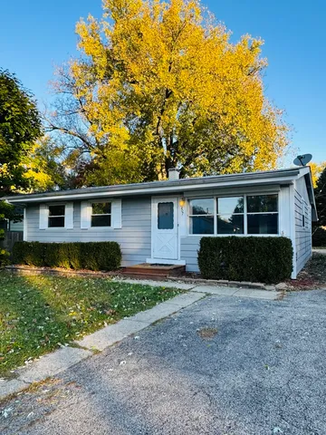 a front view of house with yard and trees in the background