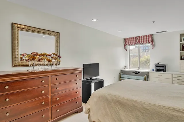 a bedroom with a bed and a large mirror on the dresser