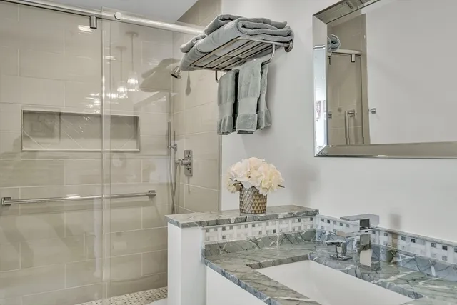 a bathroom with a granite countertop sink a mirror and shower