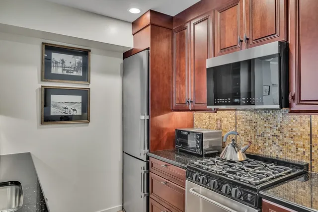 a kitchen with stainless steel appliances granite countertop a stove a refrigerator and a microwave